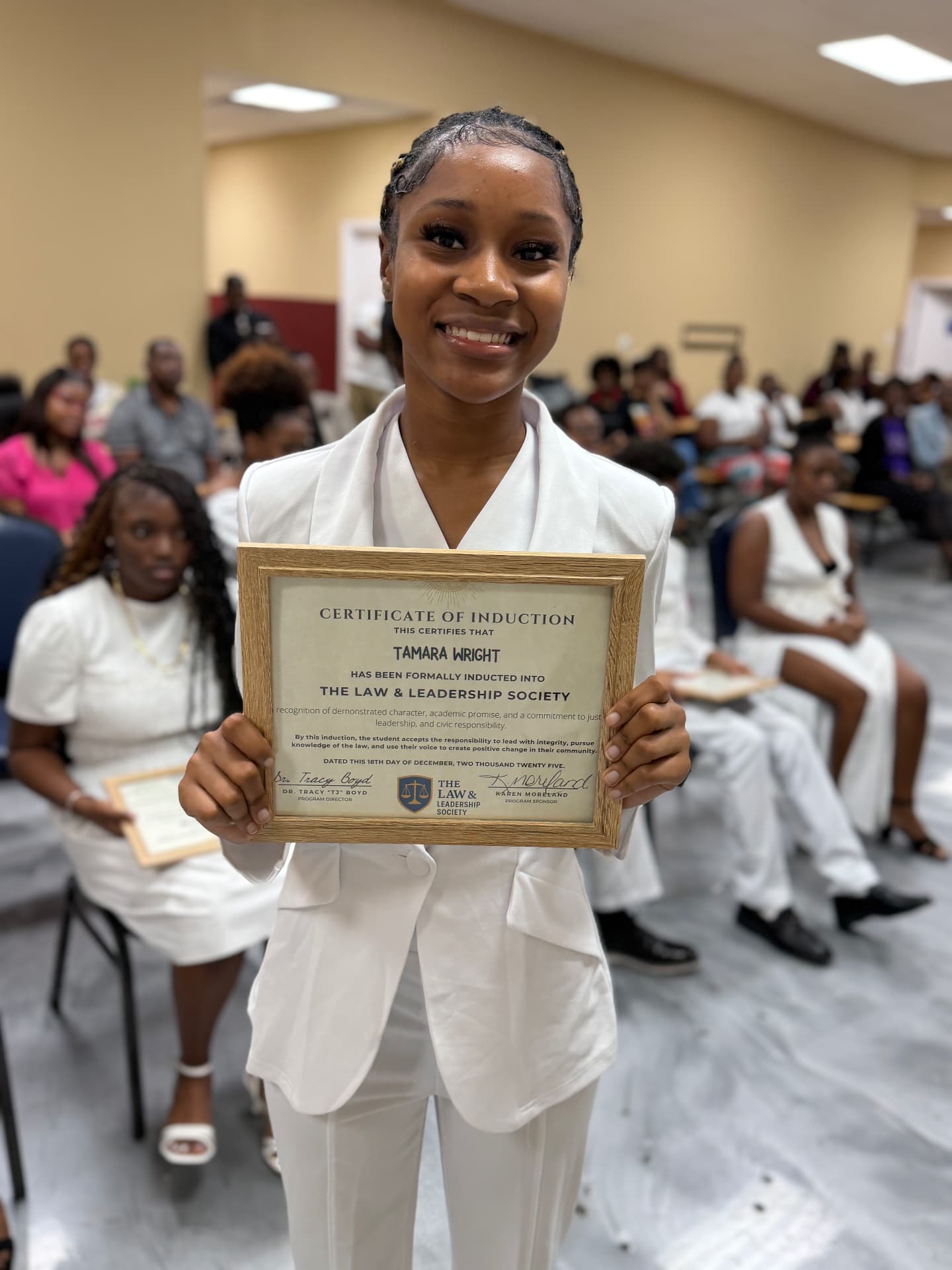 An LLS student holding a Law and Leadership Society induction certificate